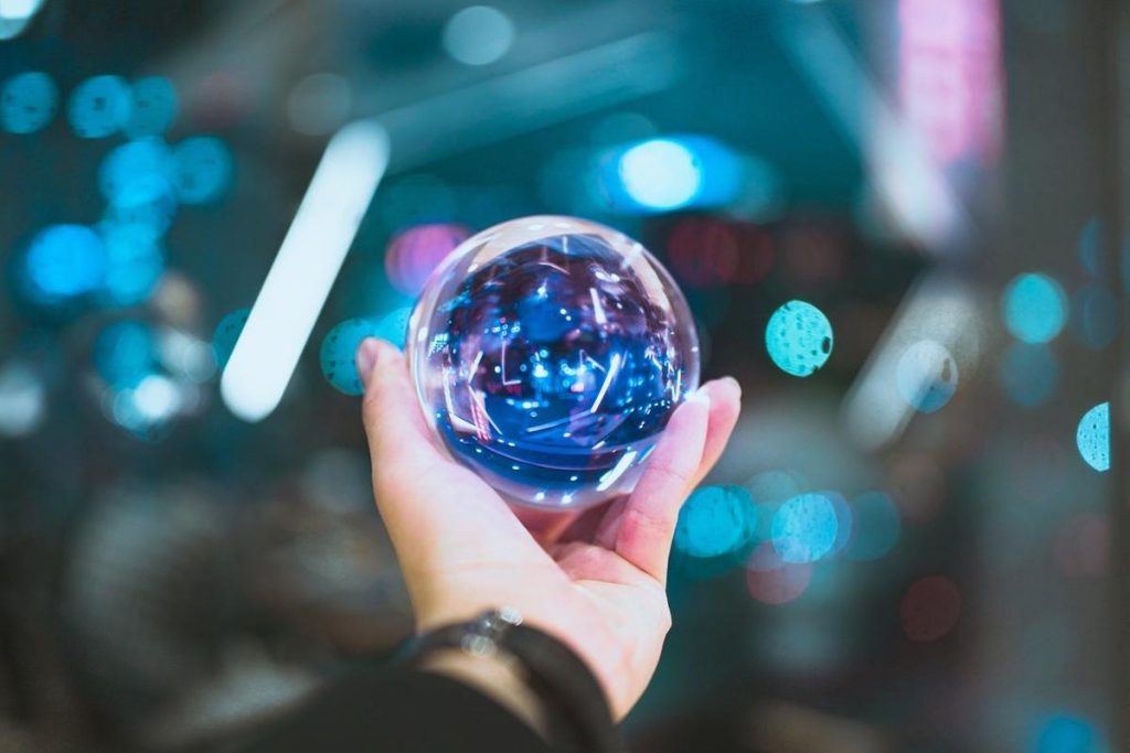 "Mano sosteniendo una esfera de cristal con luces brillantes en el fondo, simbolizando inversiones en IA."