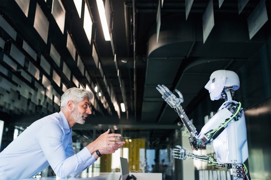Hombre interactuando con un robot en un entorno industrial.