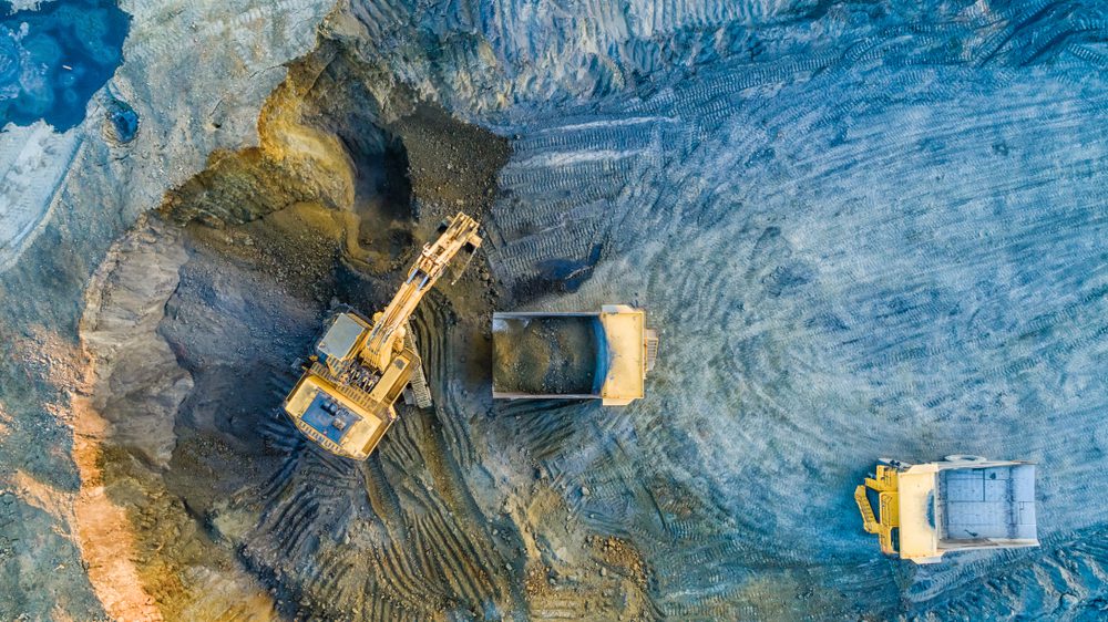 Vista aérea de maquinaria pesada trabajando en una mina, ilustrando el uso de IA y reciclaje de metales en minería."