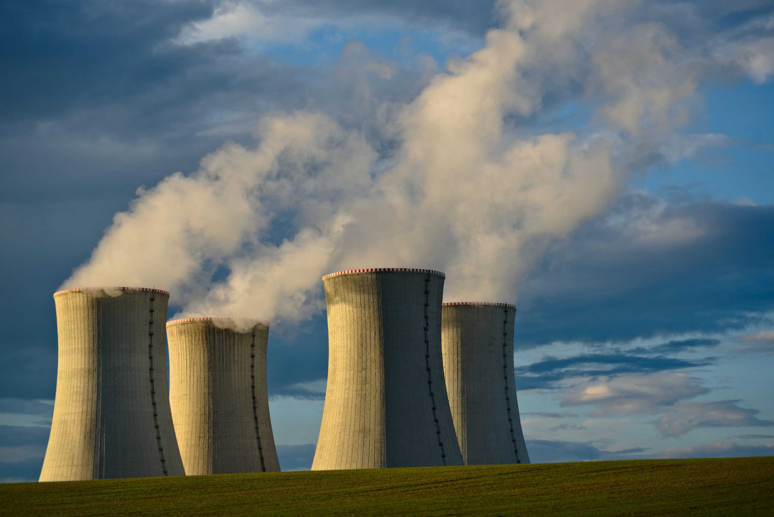 Torres de enfriamiento de una planta nuclear con humo saliendo bajo un cielo nublado.